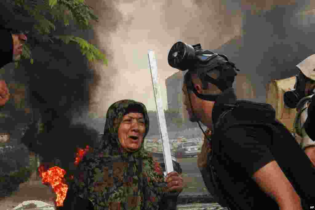 A member of the Egyptian security forces speaks to a woman holding a stick as they clear a sit-in by supporters of ousted Islamist President Mohammed Morsi, at the smaller of the two camps, near the Cairo University campus in Giza, Cairo, Egypt, August 14, 2014.