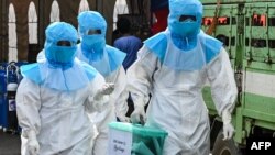 ရန်ကုန်မြို့ရှိ Quarantine စင်တာတခုမှာ ကိုဗစ်သံသယလူနာတွေရဲ့ ကြိုတင်မဲတွေကို လာရောက် ကောက်ခံတဲ့ PPE ဝတ်စုံဝတ် မဲရုံဝန်ထမ်းတချို့။ (နိုဝင်ဘာ ၀၆၊ ၂၀၂၀)