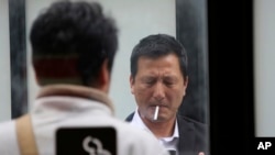 FILE - People gather at a smoking area in Tokyo, April 7, 2017.