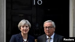 FILE - Britain's Prime Minister Theresa May welcomes Head of the European Commission, President Jean-Claude Juncker to Downing Street in London, April 26, 2017. 