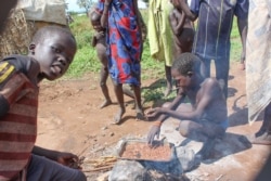 Children roast pesticide treated sorghum as source of food at Naipuru camp for internal displaced persons in Jebel Boma County. (John Tanza/VOA)