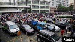 FILE - Workers protest during a strike as police stand guard at the factory area of Yue Yuen Industrial, in Dongguan, Guangdong province, April 18, 2014.