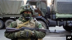 FILE - A pro-Russia rebel stands guard during preparations for a prisoner exchange in Donetsk, eastern Ukraine, Oct. 29, 2015.