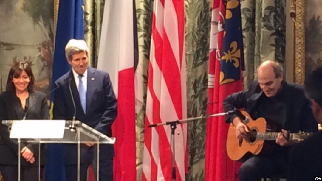 Mayor Paris Anne Hidalgo dan Menlu AS John Kerry mendengarkan lagu yang dibawakan oleh James Taylor di Balai Kota Paris dalam rangka mengenang korban teror di Paris (16/1) (Foto: Pam Dockins/VOA)