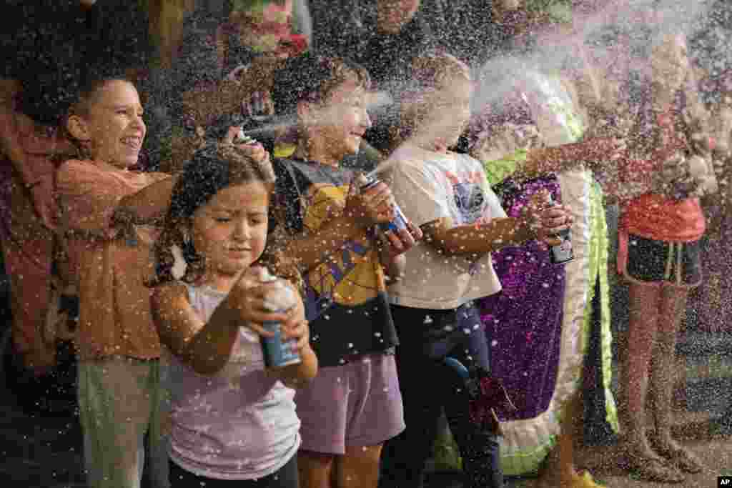 Un grupo de niños disparan espuma a participantes en un desfile de Carnaval en Montevideo, Uruguay, el 19 de febrero de 2025.