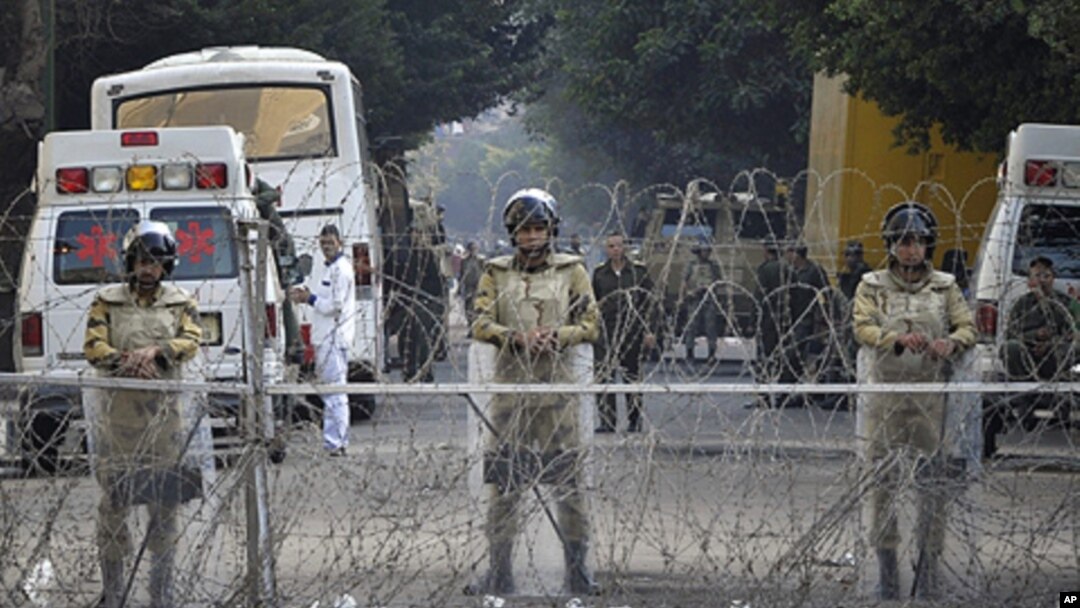 Egyptian soldiers stand behind a barbed wire fence while guarding the Cabinet building near Tahrir Square in Cairo, Egypt, Saturday, Nov. 26, 2011.