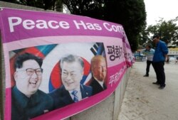A banner shows images, from left, of North Korean leader Kim Jong Un, South Korean President Moon Jae-in and U.S. President Donald Trump, displayed by protesters who demand peace on the Korean peninsula near U.S. Embassy in Seoul, South Korea.
