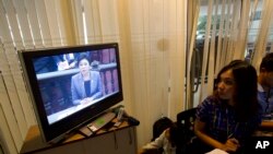 Seorang reporter sedang mengamati siaran televisi yang menayangkan jalannya sidang di Mahkamah Konstitusional Thailand, saat PM Yingluck Shinawatra menyampaikan pembelaannya, Selasa (6/5).