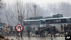 Tentara paramiliter India berdiri di dekat bus yang hancur akibat ledakan di Pampore, Kashmir yang dikuasai India, Kamis, 14 Februari 2019.