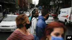 Personas que usan tapabocas esperan cruzar una calle en Caracas, Venezuela. Noviembre 4, 2020