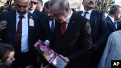A girl receives a gift from the Turkish President Recep Tayyip Erdogan in the northeastern Greek town of Komotini, Dec. 8, 2017.