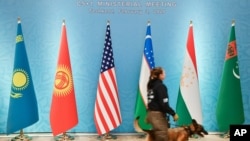 FILE - A security officer with a sniffer dog passes national flags, from left, Kazakh, Kyrgyz, U.S., Uzbek, Tajik and Turkmen, before leaders gather for a group picture during a meeting of the C5+1 in Tashkent, Uzbekistan, Feb. 3, 2020.