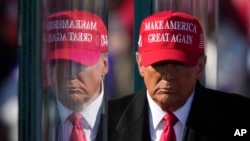 FILE - Former President Donald Trump is reflected in the bullet proof glass as he finishes speaking at a campaign rally in Lititz, Pennsylvania, Nov. 3, 2024.