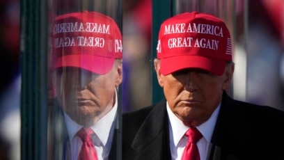 FILE - Former President Donald Trump is reflected in the bullet proof glass as he finishes speaking at a campaign rally in Lititz, Pennsylvania, Nov. 3, 2024.