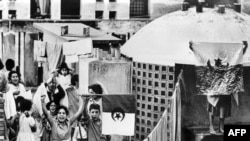 Des femmes et de jeunes enfants agitent un drapeau du FLN le 01 novembre 1961, sur un toit à Alger, pour célébrer le "Jour de l'Indépendance" et le 7e anniversaire de la rébellion algérienne.