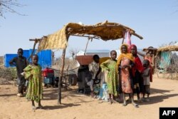 FILE—Sudanese refugees stand next to a shelter in the Farchana refugee camp, on April 7, 2024.