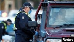 Police stop drivers at a checkpoint, set up in response to the state of Victoria's surge in coronavirus disease cases and resulting suburb lockdowns, in Melbourne, Australia, July 2, 2020. 