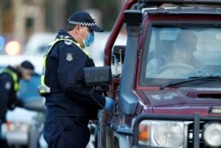 FILE - Police stop drivers at a checkpoint, set up in response to the state of Victoria's surge in coronavirus disease cases and resulting suburb lockdowns, in Melbourne, Australia, July 2, 2020.