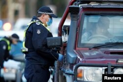 FILE - Police stop drivers at a checkpoint, set up in response to the state of Victoria's surge in coronavirus disease cases and resulting suburb lockdowns, in Melbourne, Australia, July 2, 2020.