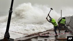 Pekerja memperbaiki pagar pembatas di pinggir pantai yang rusak dihantam ombak di Beirut, Lebanon.