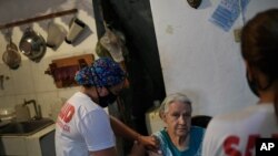 Una trabajadora de la salud inocula a una mujer con una dosis de la vacuna Sputnik V en su casa del barrio 23 de Enero en Caracas, el 12 de junio de 2021.