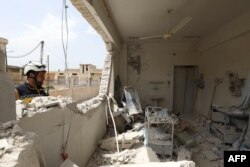 FILE - A member of the Syrian Civil Defense checks the rubble at a medical center following reported shelling by the Syrian government, in Hbeit in the southern countryside of the rebel-held Idlib province, April 30, 2019.
