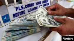 A worker counts U.S. dollar bills and Philippine pesos inside a money changer in Manila, June 19, 2013.