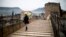 A woman crosses the old bridge in Mostar in Bosnia and Herzegovina, Jan. 20, 2013. The old bridge connects the two sides together and also has a symbolic meaning connecting the two ethnic sides of the city. 