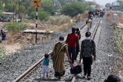 FILE - Migrant workers, desperate to return to their hometowns, walk along rail tracks towards a train station in Ahmedabad, India, May 11, 2020.