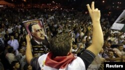 A protester holds up a poster with an image of former Egypt president Gamal Abdel Nasser during the anniversary of the 1952 Egyptian revolution at Tahrir Square in Cairo, July 23, 2012. 