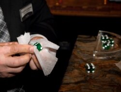 Floor supervisor Dumitru Carabasu demonstrates how to sanitize dice when there is a new shooter at a craps table at Excalibur Hotel & Casino in Las Vegas, Nevada, June 11, 2020. The casino recently reopened amid the coronavirus pandemic.