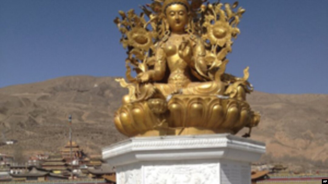 Sonam Dargye's body, covered in ceremonial scarves called katha, can be seen at the foot of the golden statue at Rongwo Temple.
