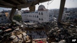 فلسطینی 10 جنوری 2024 کو جنوبی غزہ کی پٹی کے علاقےرفح میں اسرائیلی حملے کے بعد تباہ شدہ رہائشی عمارت کو دیکھ رہے ہیں۔