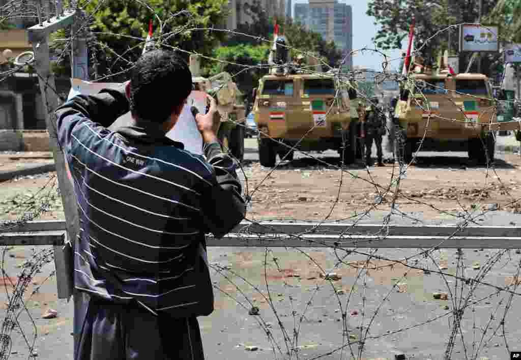 Seorang pendukung Mohamed Morsi menempelkan sebuah poster di jalan yang diblokade yang menyambung dengan gedung militer Republican Guard di Kairo, Mesir (15/7).&nbsp;(AP/Hussein Malla)