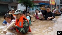 Des policiers évacuent les habitants d’une zone frappée par des inondations à Bijie, dans le soud-ouest de Guizhou, Chine, 30 juin 2006.