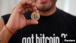 El entusiasta de Bitcoin, Carlos Bonilla, muestra una representación física de la criptomoneda, en una oficina de soporte de Bitcoin Beach en El Zonte Beach en Chiltiupán, El Salvador, el 10 de junio de 2021.