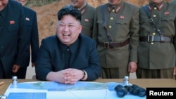 Le leader nord-coréen Kim Jon-Un entouré d’officiers de son armée, rit, avec un plan et des jumelles sur sa table, en Corée du Nord, 12 mars 2017.