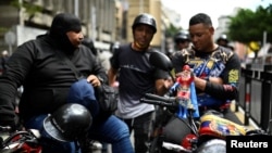 Un muñeco Super Bigote, inspirado en el presidente venezolano, Nicolás Maduro, está unido a una motocicleta de miembros de un grupo de motociclistas, conocido como Fuerza Motorizada, durante un ejercicio militar en Caracas, Venezuela, el 23 de enero de 2025. 