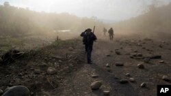 FILE - Counternarcotics officers walk in a clandestine airstrip strewn with boulders, in the Apurimac, Ene and Mantaro River Valleys, or VRAEM, the world's No. 1 coca-growing region, in Junin Peru, Sept. 19, 2014. 