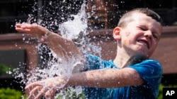 A boy cools off at a fountain outside Wrigley Field before a baseball game between the Chicago Cubs and St. Louis Cardinals as hot weather descends upon the Chicago area June 16, 2024. 