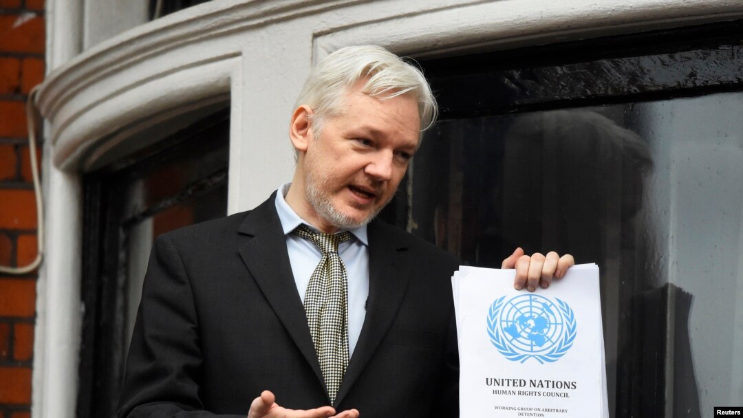 FILE - WikiLeaks founder Julian Assange holds a copy of a U.N. ruling as he makes a speech from the balcony of the Ecuadorian Embassy, in central London, Britain, Feb. 5, 2016. 