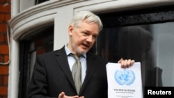 FILE - WikiLeaks founder Julian Assange holds a copy of a U.N. ruling as he makes a speech from the balcony of the Ecuadorian Embassy, in central London, Britain, Feb. 5, 2016. 