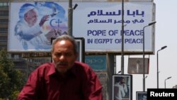 A man rides a bicycle past a billboard ahead of Pope Francis’ visit in Cairo, Egypt, April 26, 2017. (REUTERS/Amr Abdallah Dalsh)