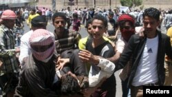 Houthi ဆန့်ကျင်ရေးသမားတွေ တိုင်ဇ်မြို့က ဆန္ဒပြပွဲအတွင်း ဒဏ်ရာရသူတဦးကို သယ်ဆောင်လာစဉ်။ (မတ်လ ၂၂၊ ၂၀၁၅)