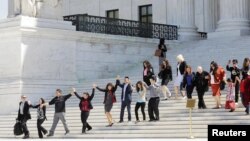 FILE - Immigration activists join hands after the US Supreme Court heard arguments in a challenge by 26 states over the constitutionality of President Barack Obama's executive action to defer deportation of certain immigrant children and parents who are in the country illegally, Washington, April 18, 2016. 