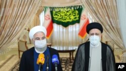 In this photo released by the official website of Iran's Presidency, President Hassan Rouhani, left, speaks with the media after his meeting with President-elect Ebrahim Raisi, right, who is current judiciary chief, in Tehran, Iran, June 19, 2021.