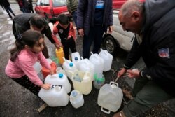 FILE - People fill plastic containers with water from a tap in Damascus, Syria, Jan. 16, 2017.