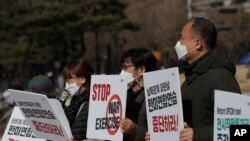 South Korean protesters hold signs during a rally to oppose the joint military exercises between South Korea and the United States near the presidential Blue House in Seoul, South Korea, March 8, 2021.