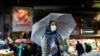 FILE PHOTO: An Iranian woman wears a protective face mask and gloves, amid fear of coronavirus disease (COVID-19), as she walks at Tajrish market, ahead of the Iranian New Year Nowruz, March 20, in Tehran
