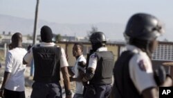 Police officers detain two demonstrators during a protest at the Cite Soleil slum in Port-au-Prince, Haiti, December 24, 2011.